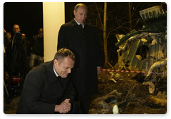 Russian Prime Minister Vladimir Putin and Polish Prime Minister Donald Tusk lay flowers next to a piece of the wreckage from the Tu-154 plane crash