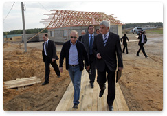 Prime Minister Vladimir Putin surveys the progress of housing construction for wildfire victims in the village of Ivatino in the Vladimir Region and talks with future residents